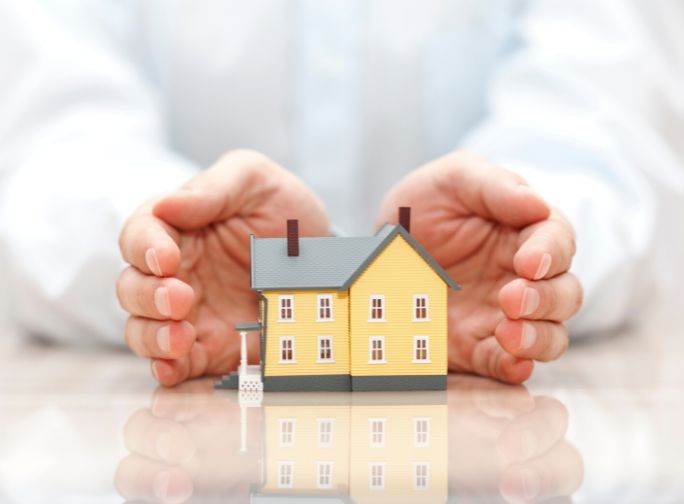person holding a scale model of a house in both hands